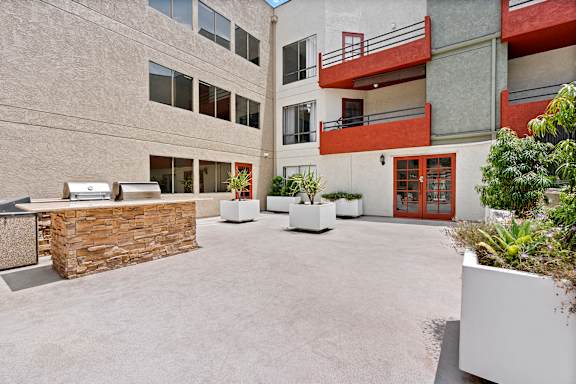 A courtyard with a stone wall and potted plants at Woodland Trio Apartments, California.