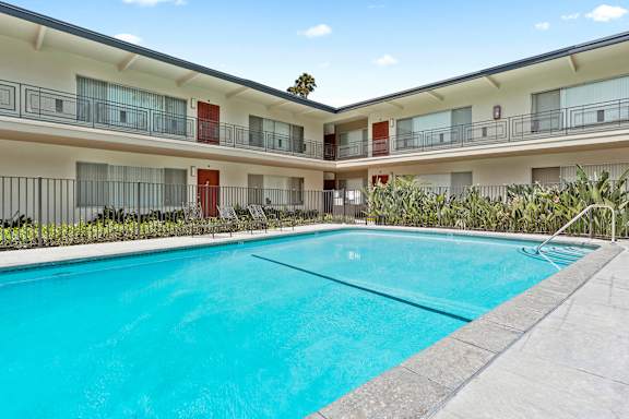A large swimming pool in front of a building with balconies.