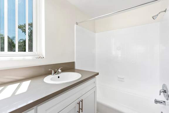 A white bathroom with a sink and a bathtub.