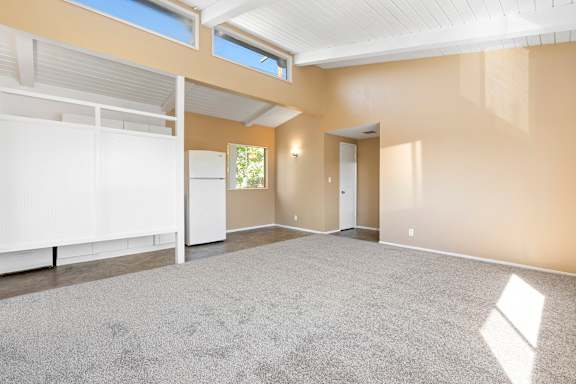 an empty living room with a carpeted floor and a window
