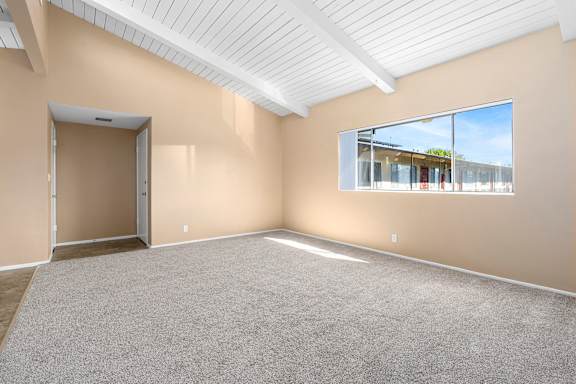 an empty living room with carpet and a large window