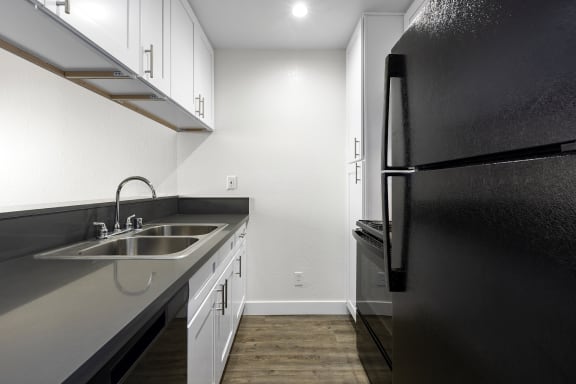 an empty kitchen with a sink and a refrigerator