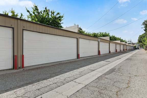 A row of garage doors are closed and lined up on a street.