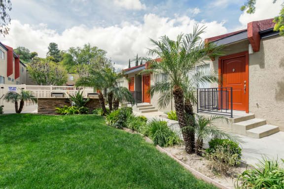 a house with orange doors and a lawn and palm trees