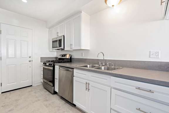 A kitchen with white cabinets and stainless steel appliances.