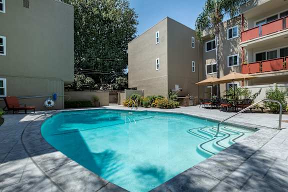 A swimming pool in a backyard surrounded by buildings.