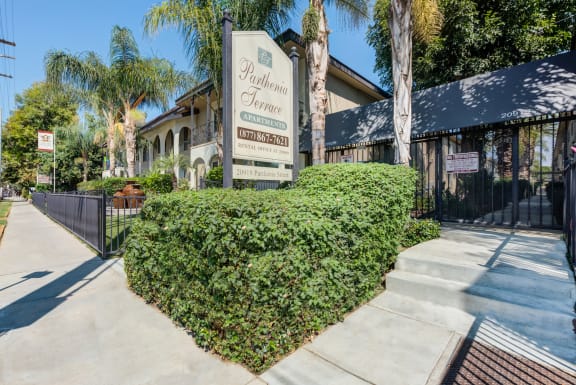 a building with a sign and a hedge in front of it