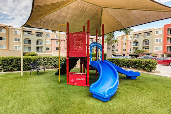 A playground with a blue slide and a red sign that says "snacks".