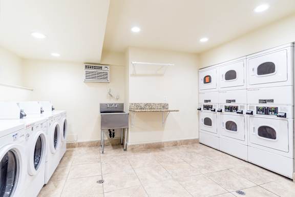 A laundry room with a washer and dryer on the left and a row of ovens on the right.