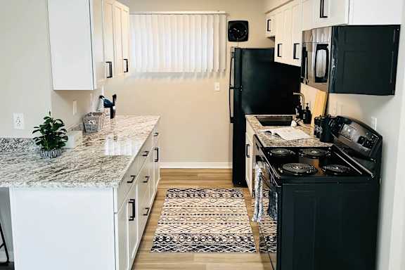 A kitchen with black appliances and white cabinets at Eton Square Apartments and Townhomes, Birmingham