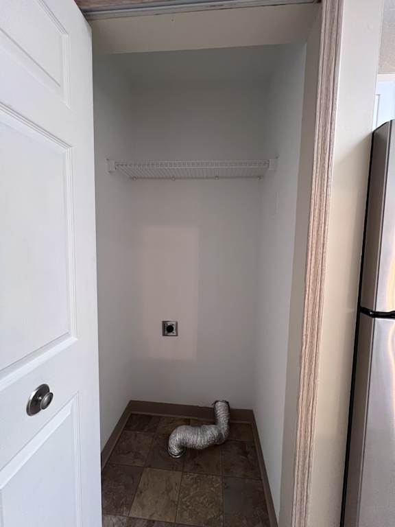 A white door is open to a small room with a white wall and a silver pipe on the floor.