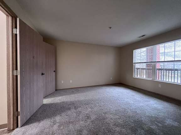 A room with a carpeted floor and a large window.