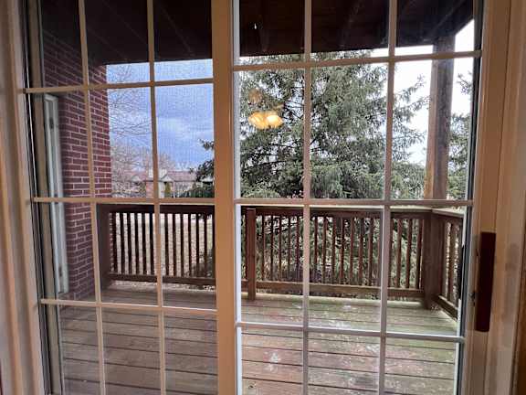 A view from a window looking out to a deck and trees.