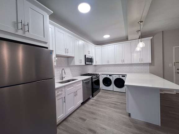 A modern kitchen with white cabinets and a stainless steel refrigerator. at Huntington Green Apartments, University Heights, Ohio