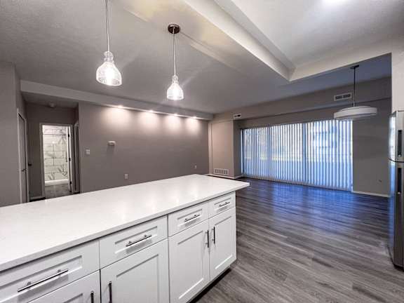 an open kitchen and living room with a large window and white counter tops