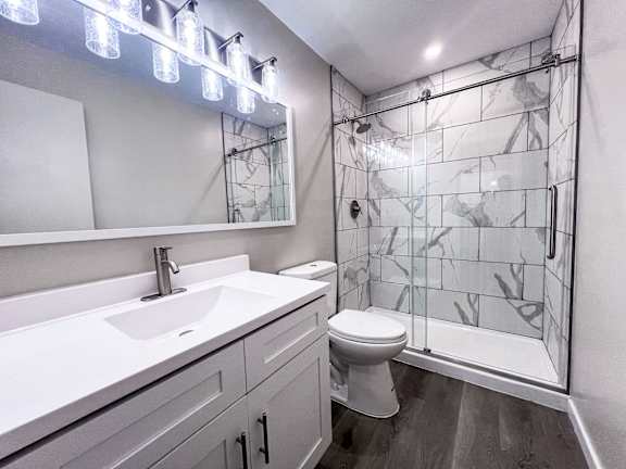 A bathroom with a white sink, toilet, and glass block shower. at Huntington Green Apartments, University Heights, OH
