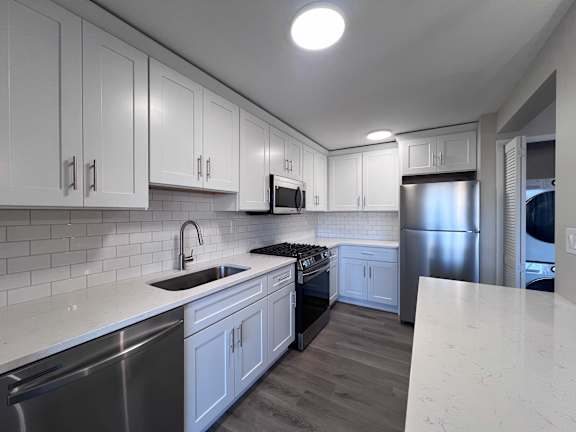 a kitchen with white cabinets and stainless steel appliances at Huntington Green Apartments, University Heights, OH