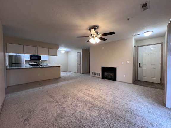 A living room with a fireplace and a ceiling fan.
