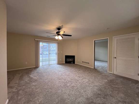 A room with a ceiling fan and a fireplace.