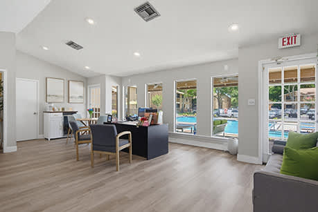 A spacious room with a desk, chairs, and a view of the pool outside.