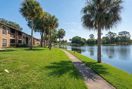 A walkway runs along a grassy area next to a body of water.