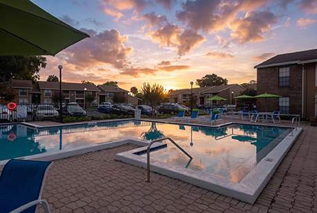 A sunset view of a pool area with a slide.