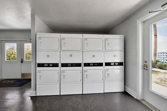 A row of white washing machines are lined up in a laundry room.