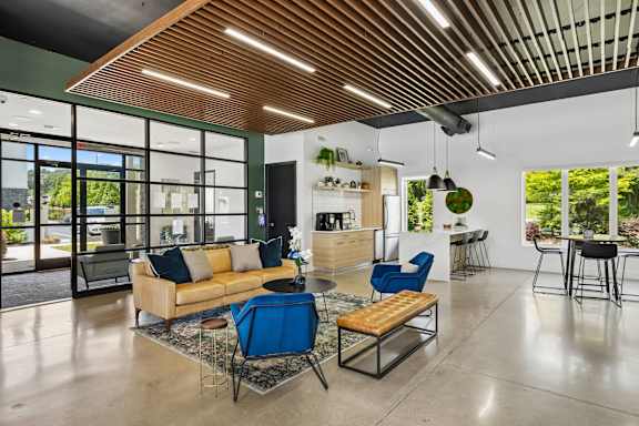 A modern living room with a blue chair and a wooden ceiling.