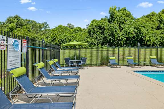 A pool area with sun loungers and a green umbrella.