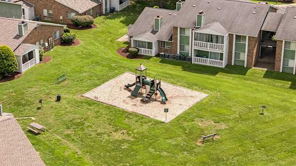 A park with a playground in the middle of a grassy area.