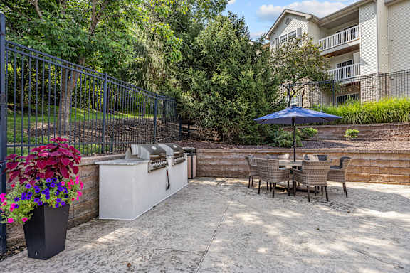 A patio with a table and chairs and a blue umbrella.