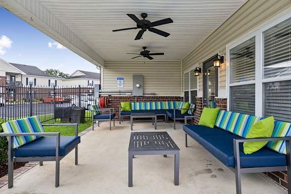 A patio with a blue couch and a fan.