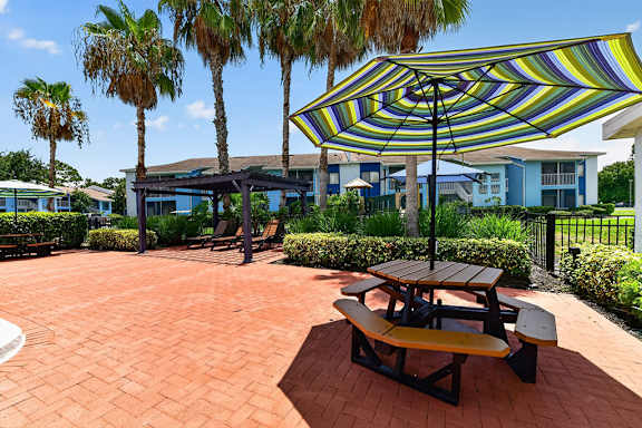 A patio with a table and chairs under a striped umbrella.
