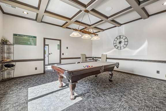 A room with a pool table and a clock on the wall.