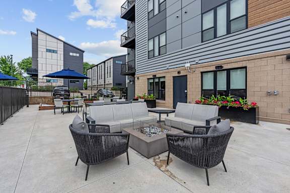 A patio with a table and chairs is surrounded by modern buildings.