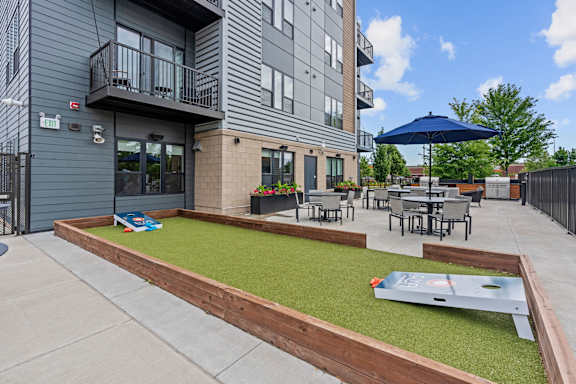A patio area with a mini golf table and a blue umbrella.