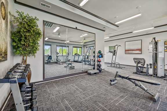 A spacious gym with a variety of equipment and a mirrored wall.