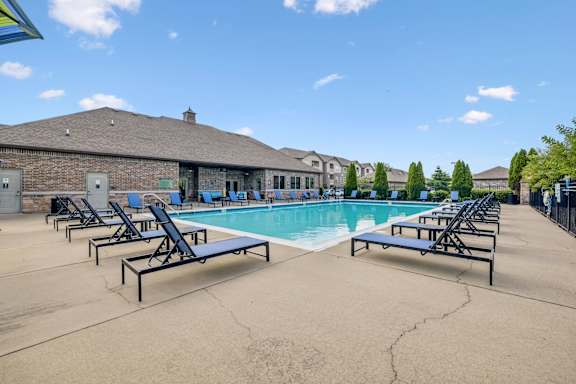 A pool with sun loungers and a building in the background.