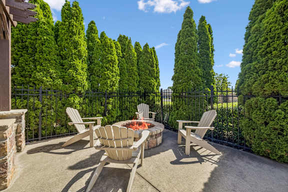 A patio with a fire pit surrounded by trees.
