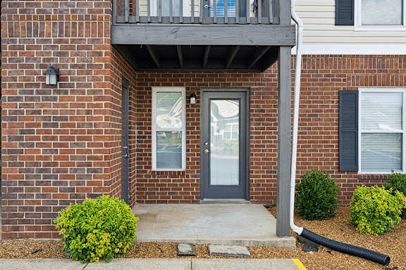 A brick house with a grey door and windows.