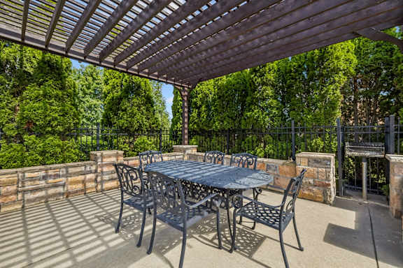 A patio with a table and chairs under a pergola.