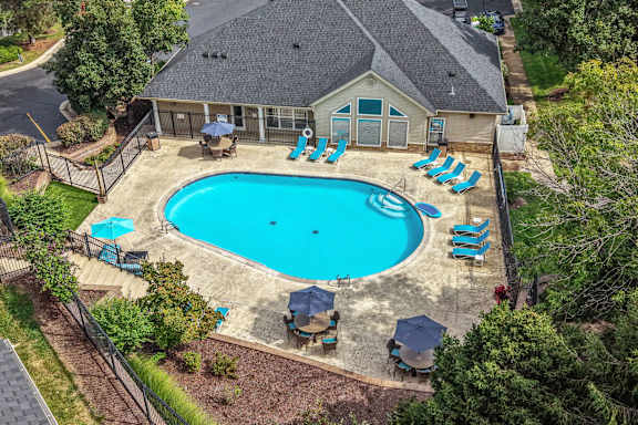 A pool surrounded by a fence and chairs.
