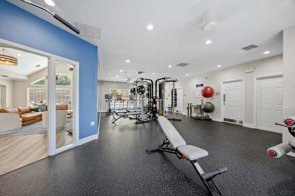 A gym with a bench, weights, and exercise equipment.