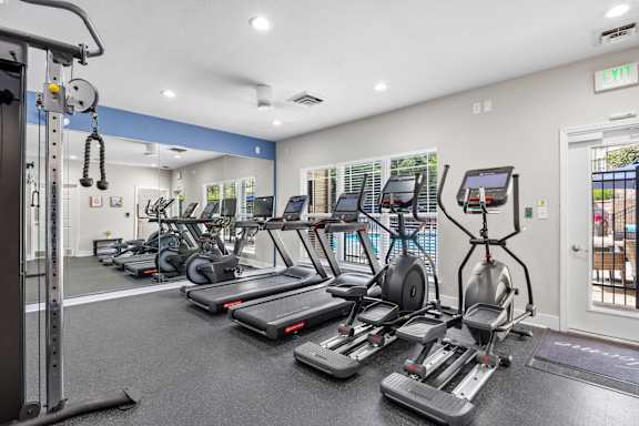 A gym with treadmills, elliptical machines, and other exercise equipment.