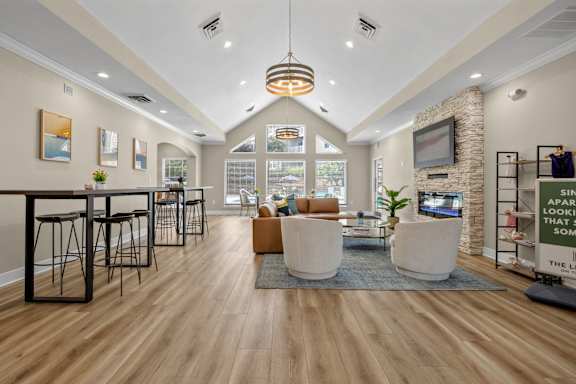 A living room with a stone fireplace and a flat screen TV mounted on the wall.