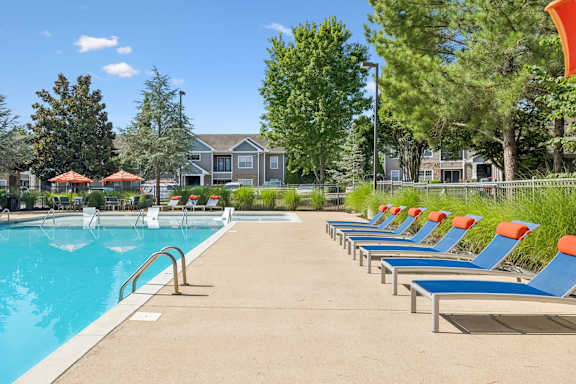 A pool with blue chairs and a red umbrella.
