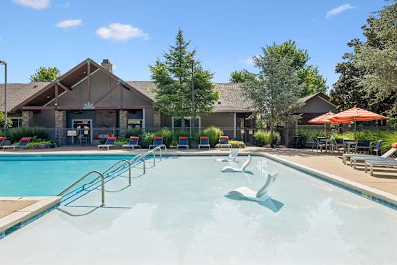 A large swimming pool with a slide and a building in the background.