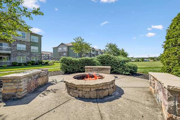 A fire pit sits in the middle of a concrete patio.
