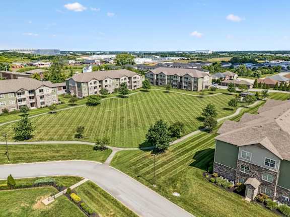 A large grassy area with a road and apartment buildings in the background.