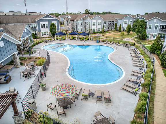 A large outdoor swimming pool surrounded by lounge chairs and umbrellas.